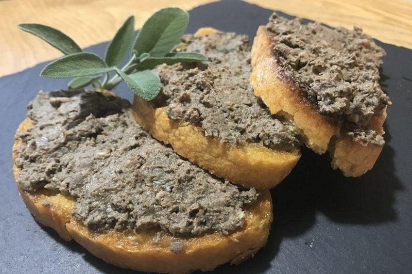 Tre skivor rostat bröd med ett pålägg, serverat på en mörk tallrik, tillsammans med en kvist salvia. 2