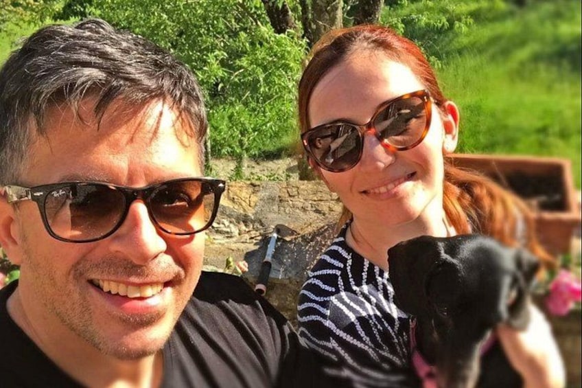 En person som håller i en svart hund, med grönska och en stenmur i bakgrunden. 4