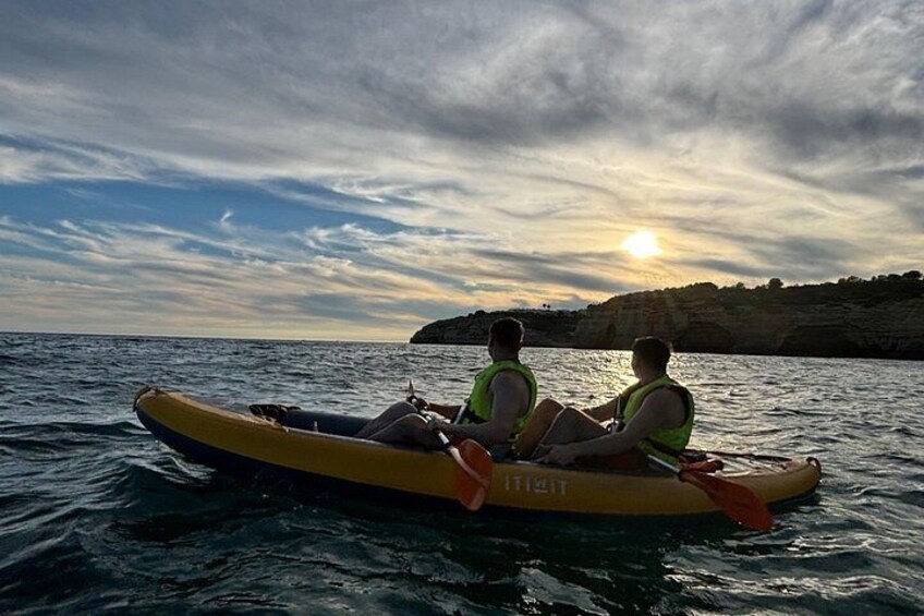 Deux personnes se trouvent dans un radeau gonflable jaune sur une étendue d’eau calme, avec un coucher de soleil en arrière-plan. 2