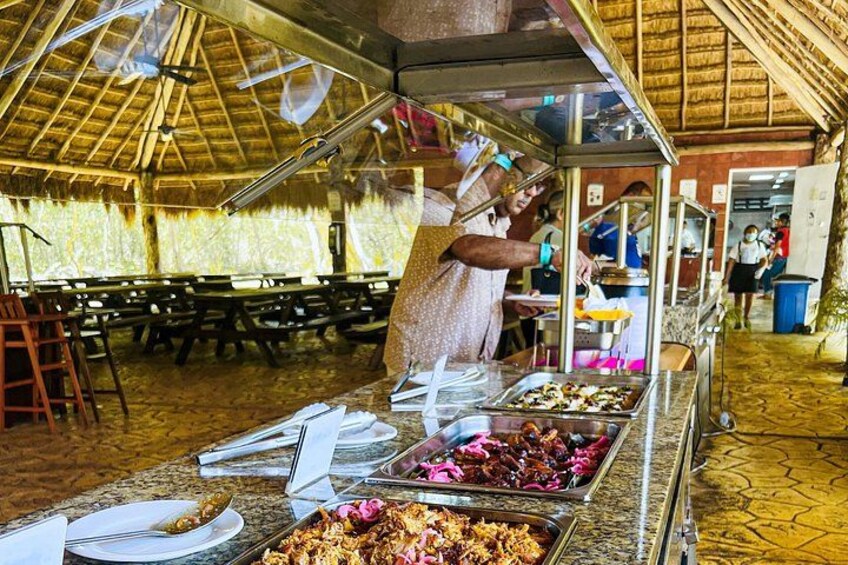 Montaje tipo buffet con fuentes de comida y una persona sirviendo. 5