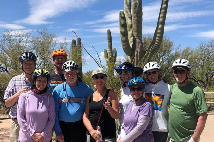 A group of people wearing helmets, standing in front of cacti. 1