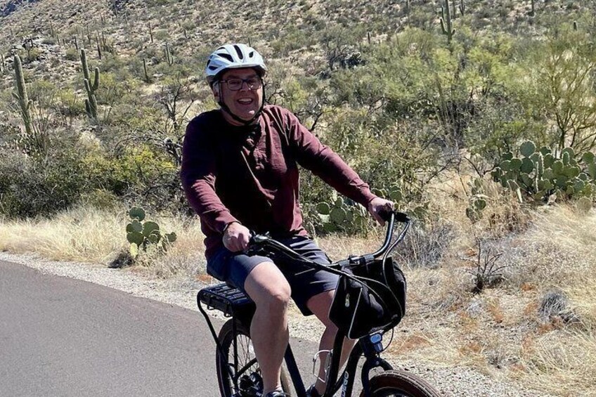 Eine Person fährt Fahrrad auf einer Straße, im Hintergrund eine Wüstenlandschaft. 5