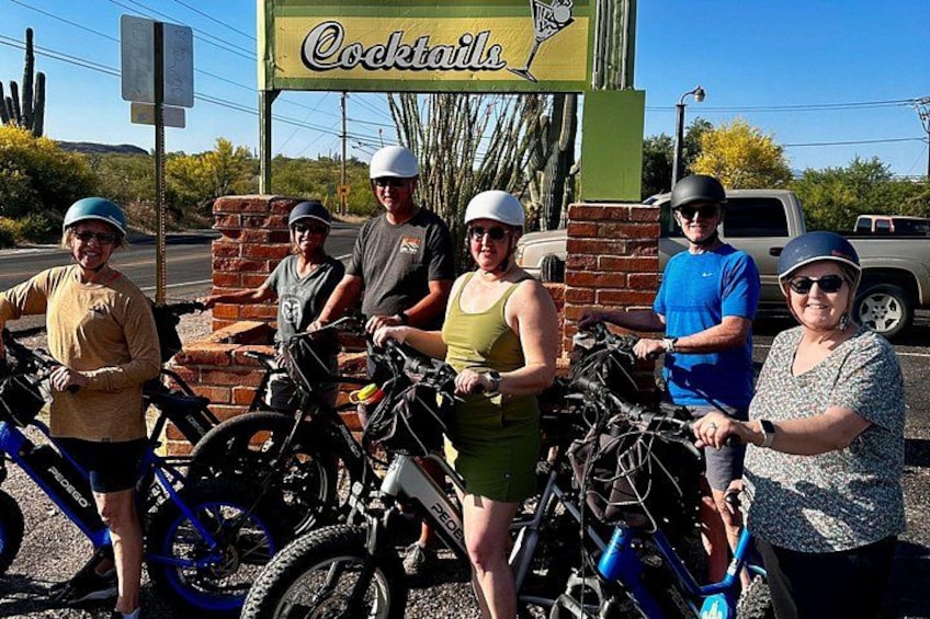 A group of people with bicycles in front of a restaurant named 'Cocktails'. 3