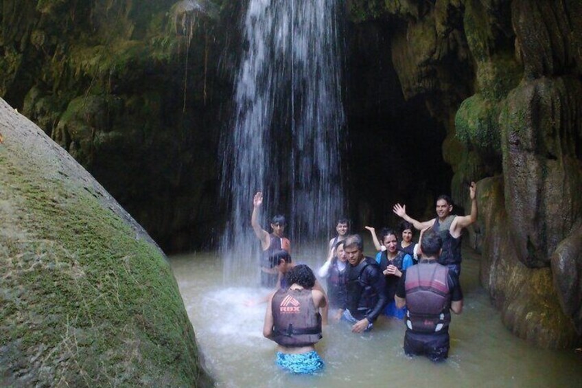 A group of people in a cave with a waterfall. 1