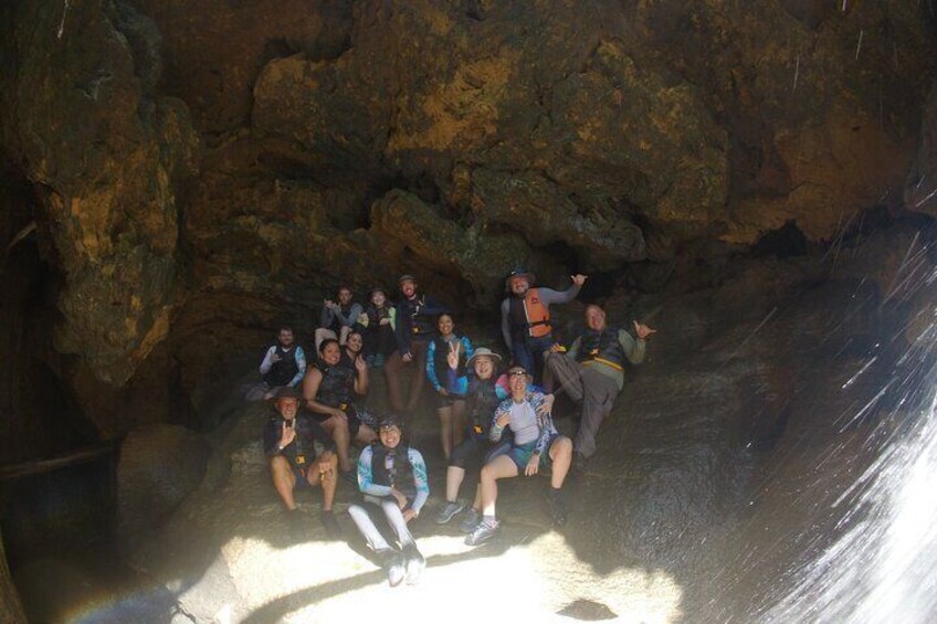 A group of people inside a cave with rocky walls and a water stream. 5
