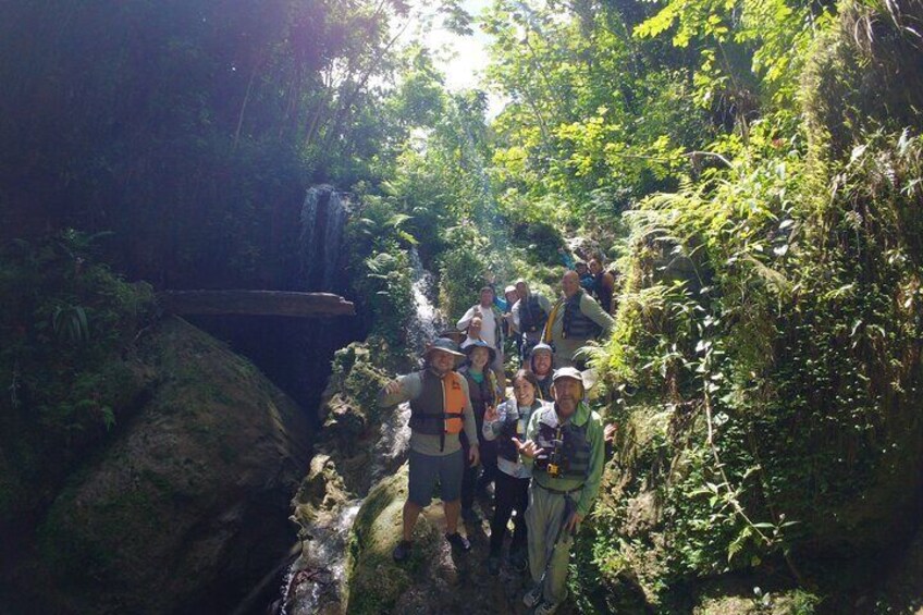 A group of hikers on a forested trail with a waterfall. 4