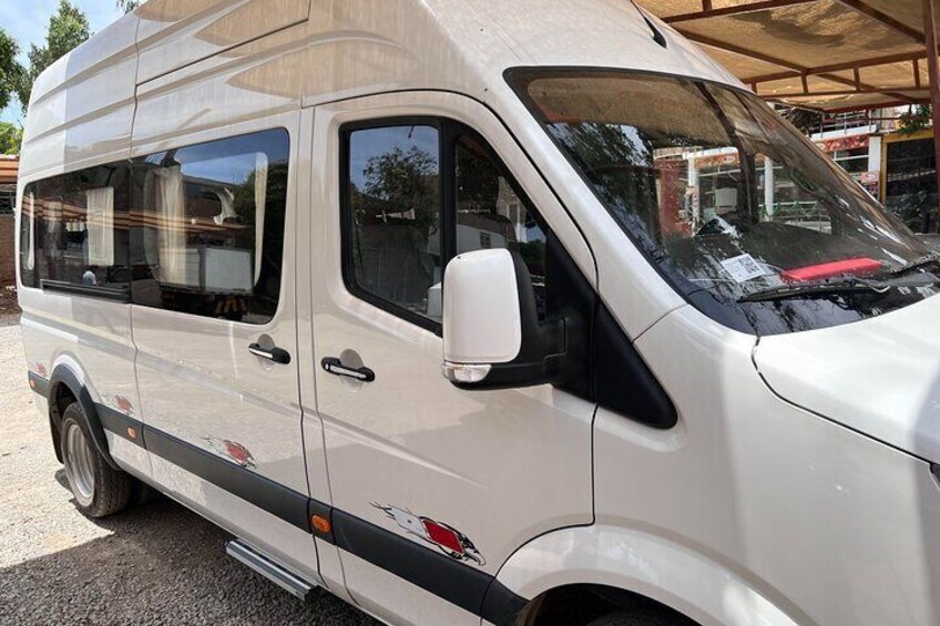 A white van parked outdoors with a side mirror, windows, and a rearview mirror. 3