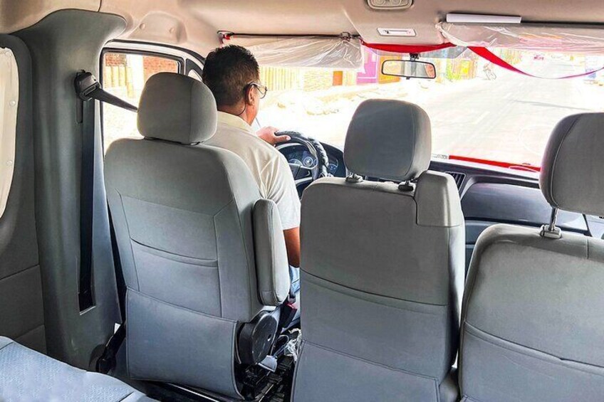 The interior of a vehicle with two grey seats, a steering wheel, and a dashboard. 2