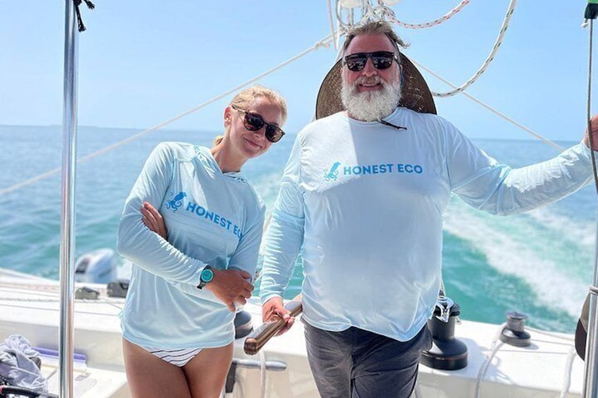 Two people on a boat wearing 'Honest Eco' shirts, with the ocean in the background. 1