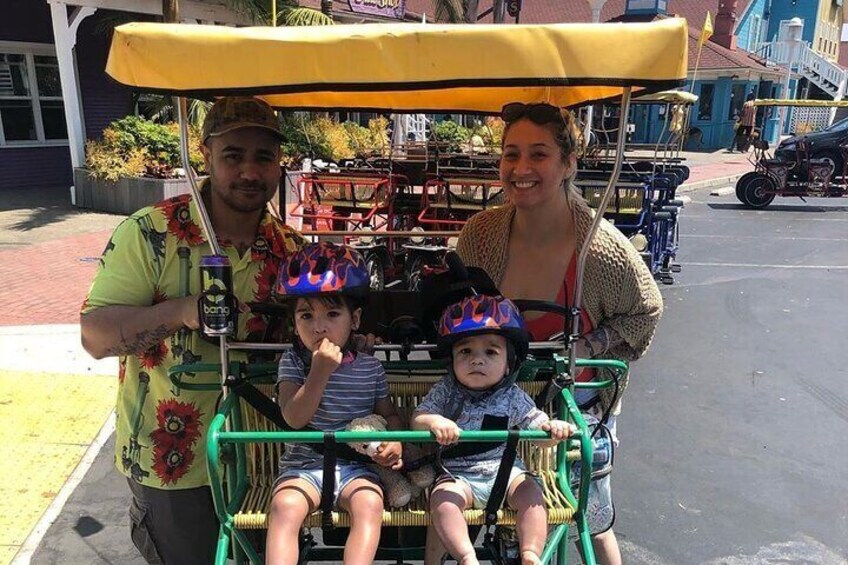 A family on a green and yellow trolley with a child wearing a colorful helmet. 2