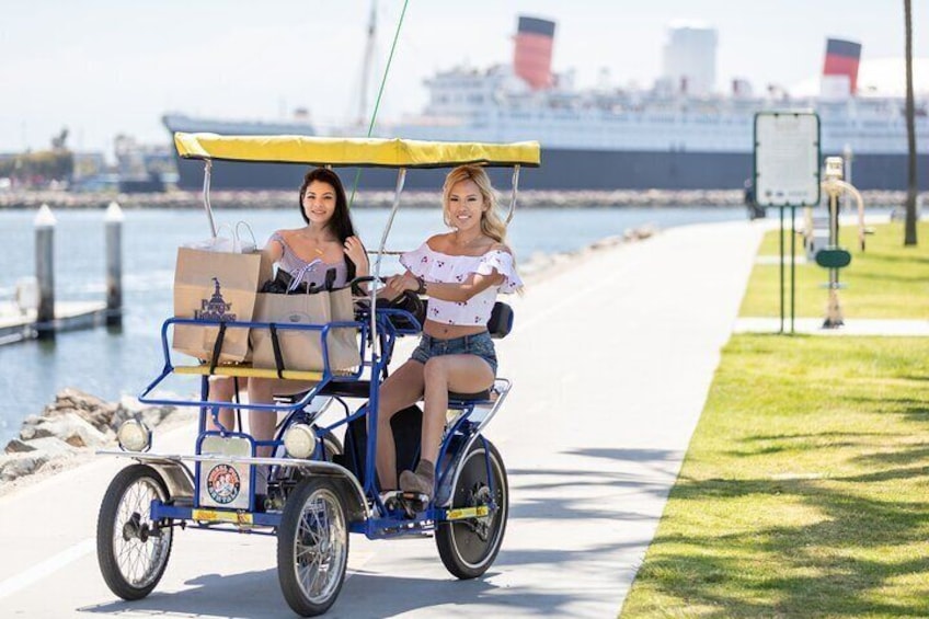 A person riding a blue cart with a yellow canopy along a waterfront path. 4