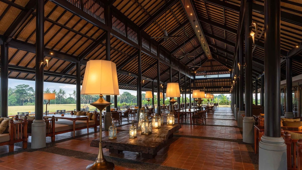An indoor dining area with wooden tables and chairs, large lamps, and lanterns. 2