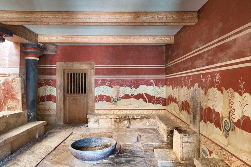An ancient room with red walls, a wooden door, and a stone basin. 3