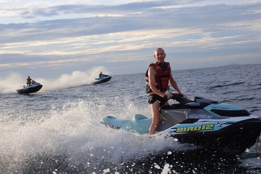 Une personne sur un jet ski, portant un gilet de sauvetage, un autre jet ski en arrière-plan et une étendue d'eau. 1