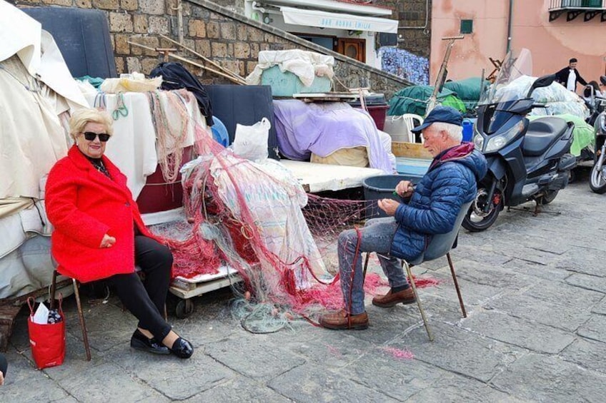 Two people sitting at a table outdoors, surrounded by various items and a scooter. 2