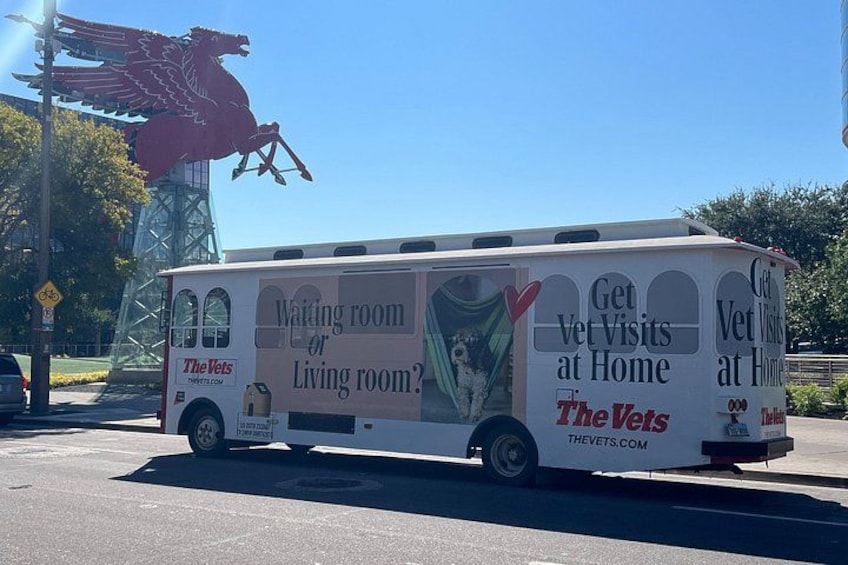 A white bus with advertisements for The Vets, parked on a street. 5