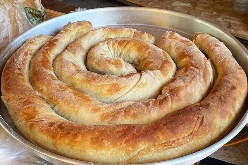 A large, spiral-shaped pastry on a metal tray. 1