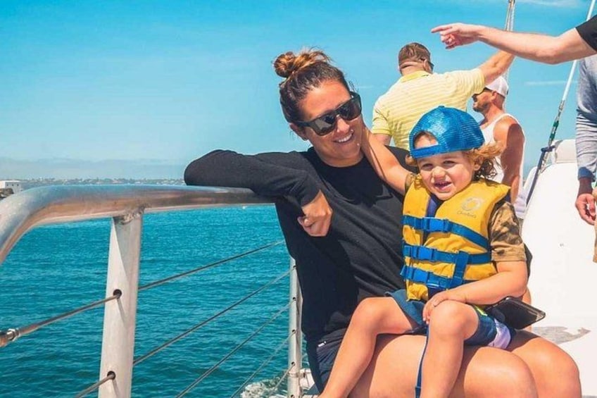 A person in a black top and sunglasses, sitting on a boat with a child in a yellow life jacket. 5