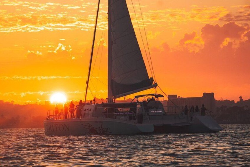 A sailboat with people on board during sunset. 4