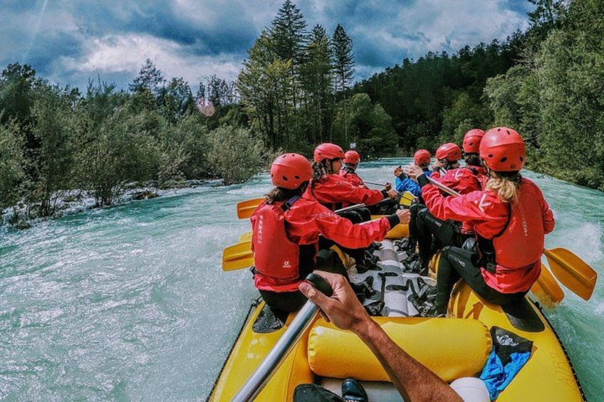 Eine Gruppe von Menschen in einem gelben Schlauchboot auf einem von Bäumen gesäumten Fluss. 1
