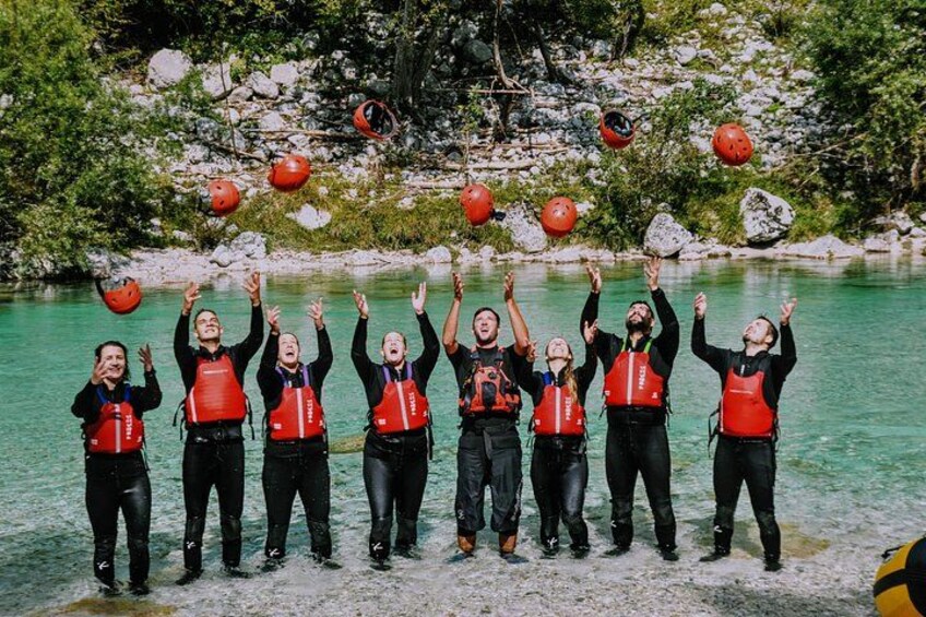 Eine Gruppe von Personen in schwarzen Neoprenanzügen und roten Schwimmwesten steht an einem klaren, blauen See. Im Hintergrund sind Felsen und Grünpflanzen zu sehen. 2