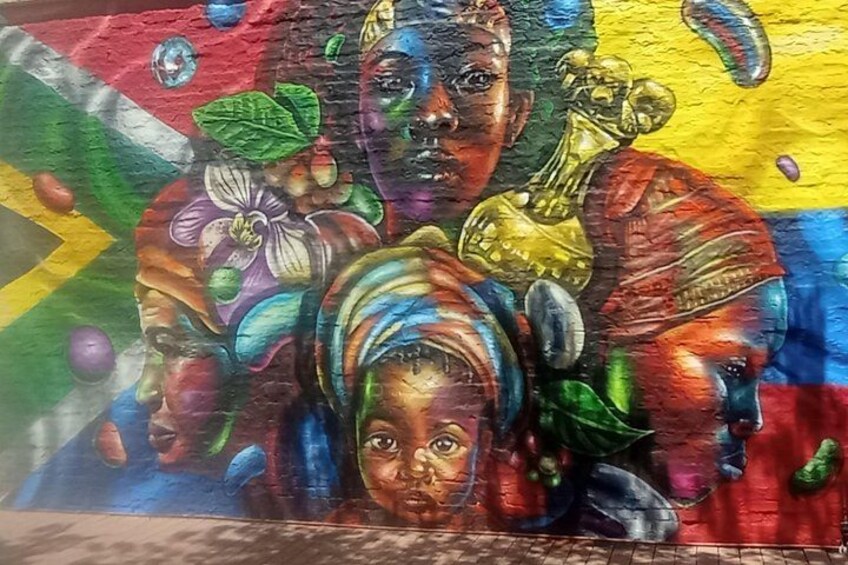 Une fresque colorée représentant des figures humaines abstraites et des motifs floraux. 4