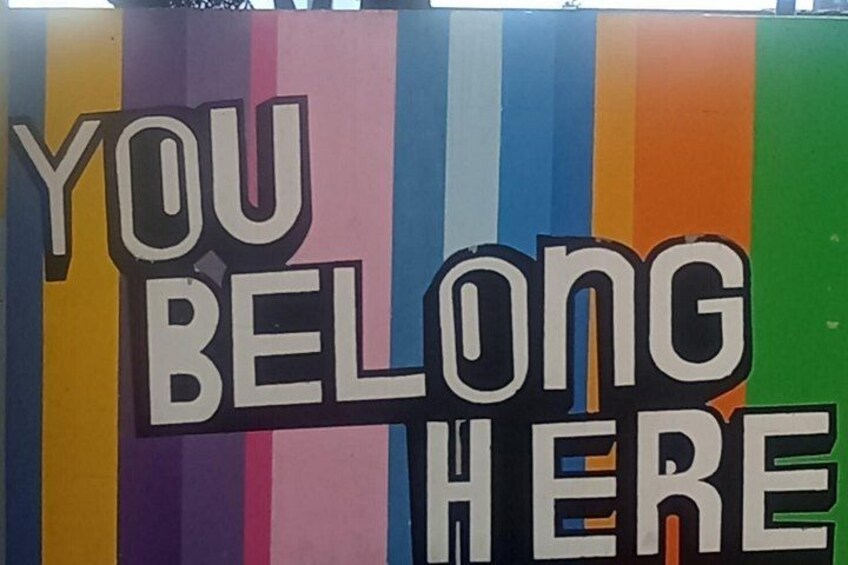 Une enseigne colorée sur laquelle on peut lire : « VOUS ÊTES LES BIENVENUS ICI ». 3