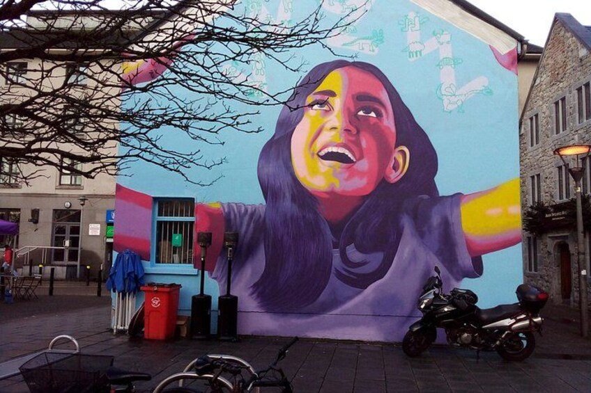 A mural on a building, a motorcycle parked in front, and a bicycle. 3
