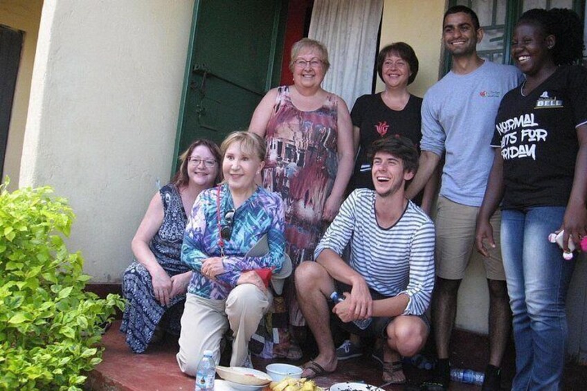 A group of people sitting and standing on a porch with a green door and a potted plant. 4