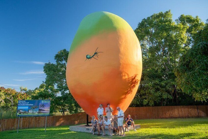 A large, colorful balloon sculpture with a person climbing it, surrounded by a group of people. 4