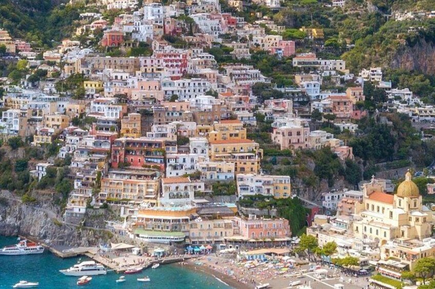 A coastal town with colorful buildings, a harbor with boats, and a hillside with greenery. 2