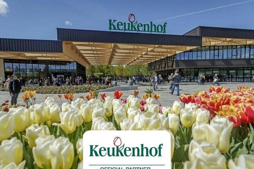 En blomsterhave i Keukenhof med en moderne bygning i baggrunden. 1