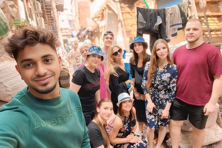 Eine Gruppe von Menschen in einer offenen Umgebung mit Gebäuden und einer schmalen Straße. 4
