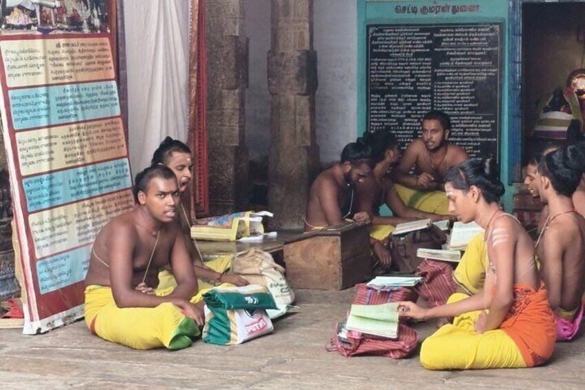 A group of people sitting on the floor in a room with books and papers, some writing and some reading. 4