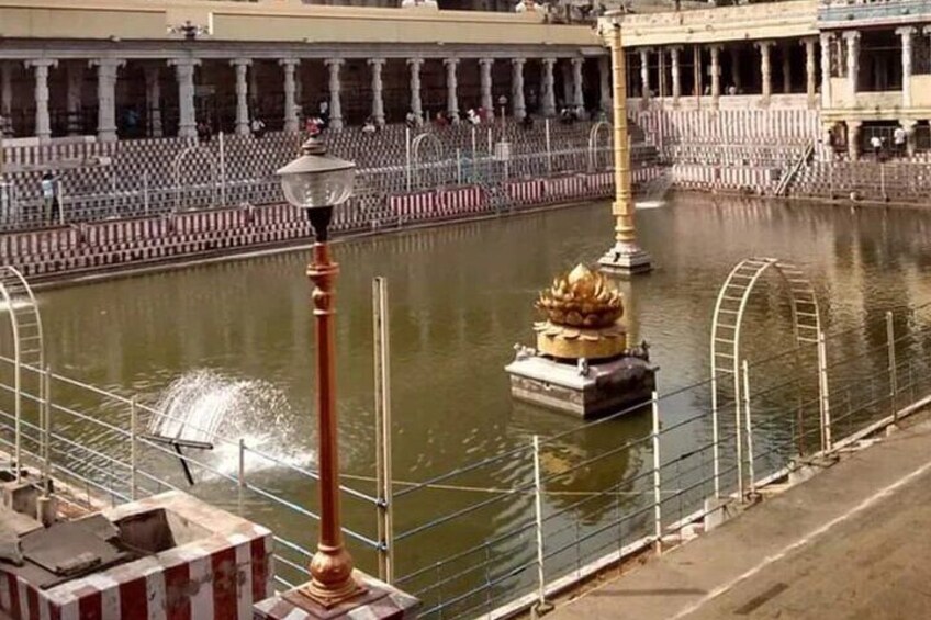 A water fountain with a golden statue, a lamp post, and a row of columns in the background. 2