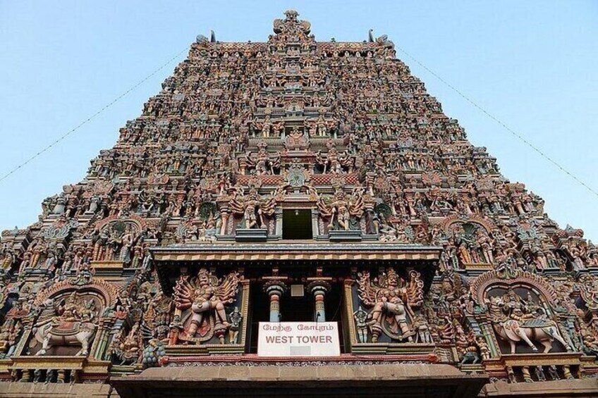 A detailed temple with intricate carvings and a sign reading 'West Tower.' 1