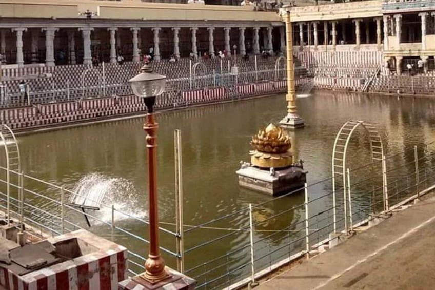 A water body with a lotus-shaped structure, a lamp post, and a building with columns in the background. 2