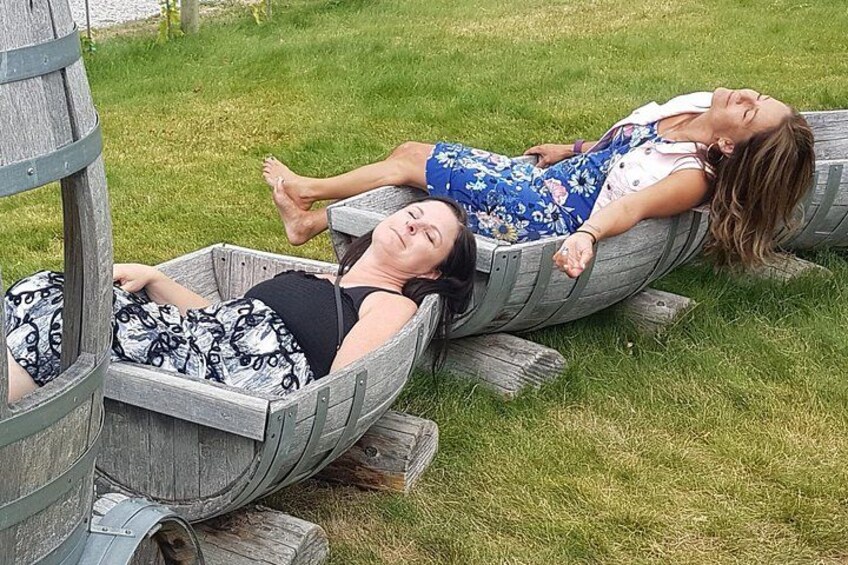 Two people lying in wooden boats on grass. 5