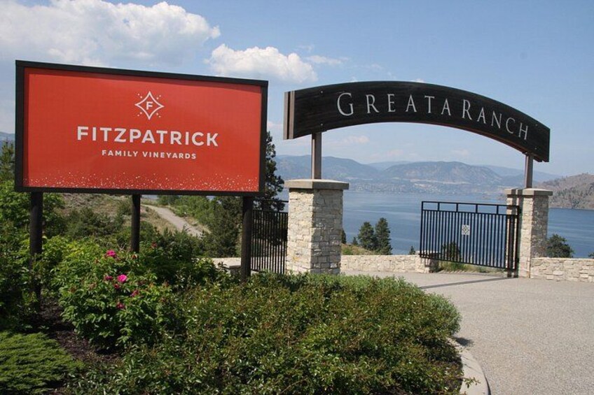 A sign for Fitzpatrick Family Vineyards with a view of a lake and mountains in the background. 4