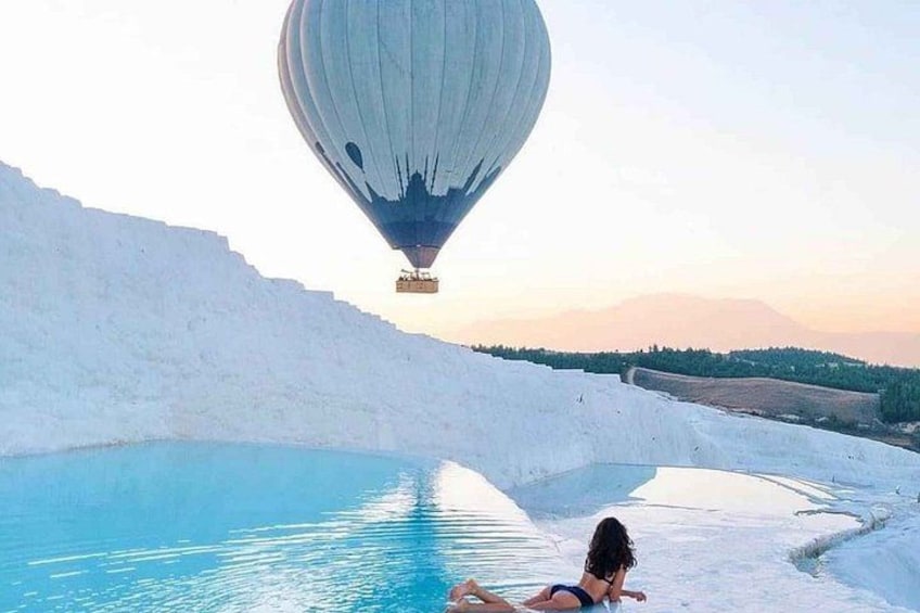 A person relaxing by a pool with a hot air balloon in the background. 1
