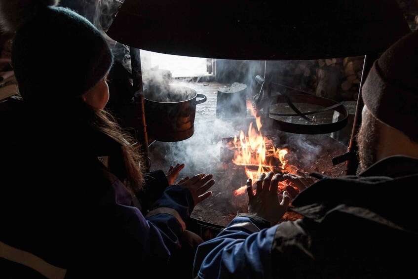 Una persona cocinando sobre fuego abierto, con ollas y sartenes. 4
