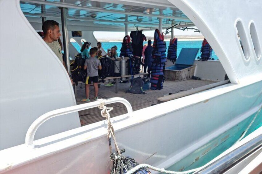 A boat deck with people preparing for a water activity, life jackets, and a rope. 4