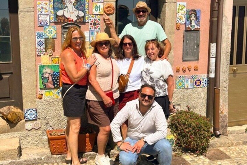 Un grupo de personas posando frente a un edificio con azulejos de colores y una puerta. 5