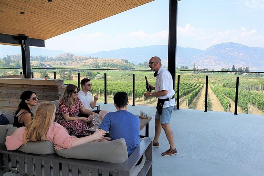 Un groupe de personnes est assis sur une terrasse, avec un vignoble en arrière-plan. 5