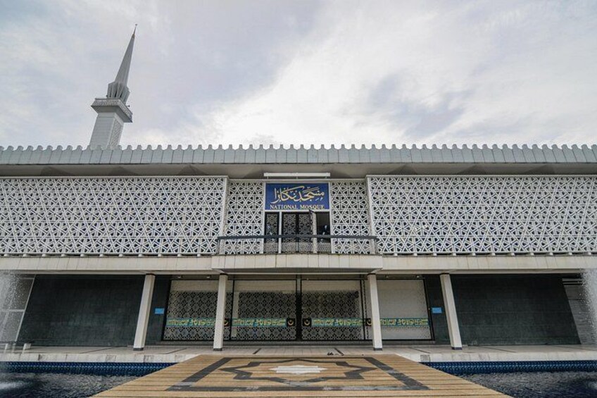 A mosque with a minaret, a patterned entrance, and a sign reading 'National Mosque'. 2