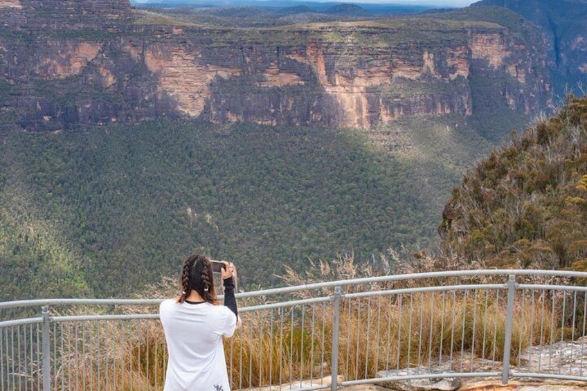 A person taking a photo of a canyon landscape. 5