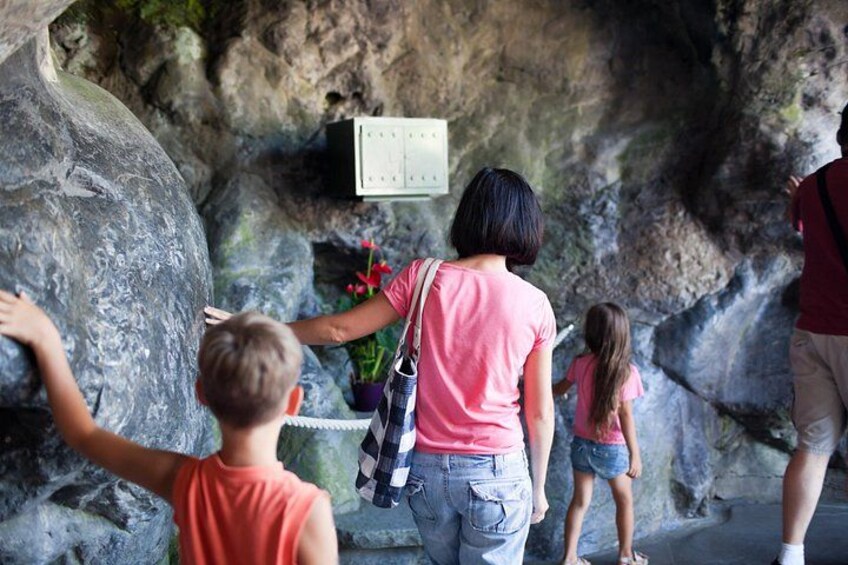 A group of people exploring a rocky cave with a calendar on the wall. 2