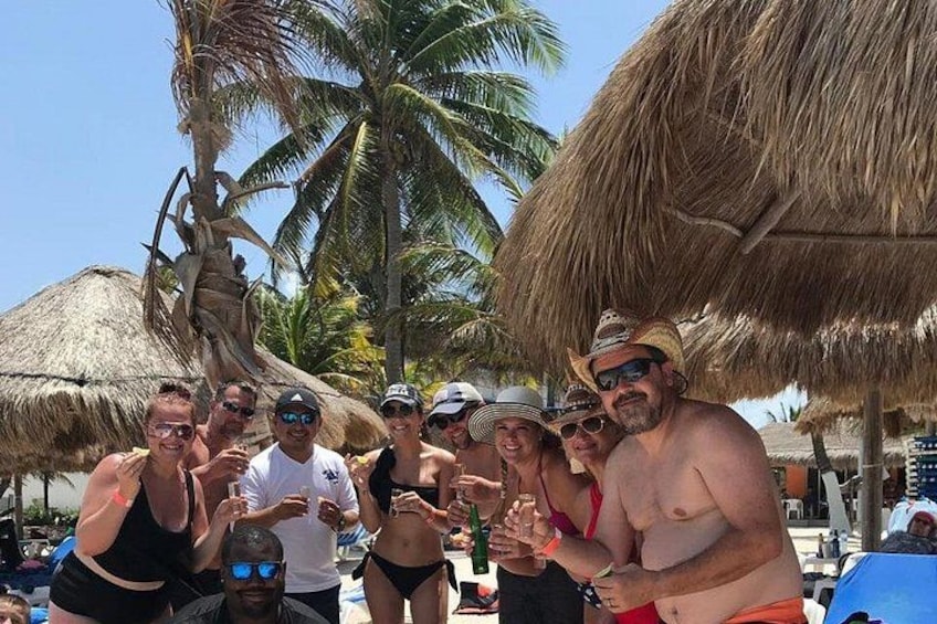 Un groupe de personnes se trouve sur une plage, avec des palmiers et des parasols en chaume. 4