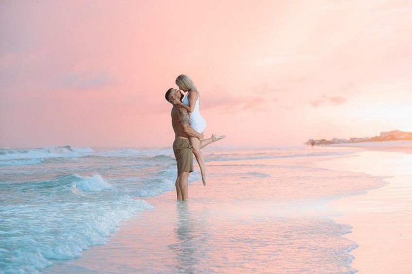 A couple on a beach with the ocean and a sunset in the background. 3