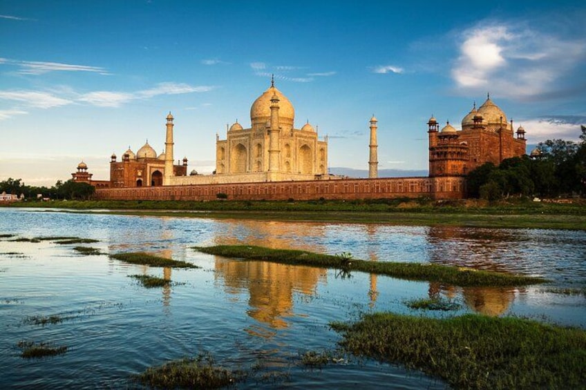 The Taj Mahal with its reflection in the water, surrounded by a moat and greenery. 4